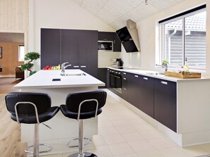 A modern kitchen with a central island, bar stools, and a window providing natural light. - Holiday Home in Kappeln (Kappeln)