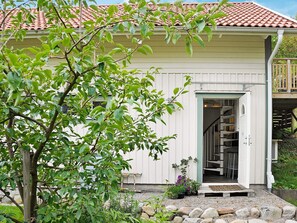 A white building with a tiled roof, a wooden deck, and a stone pathway leading to the entrance.