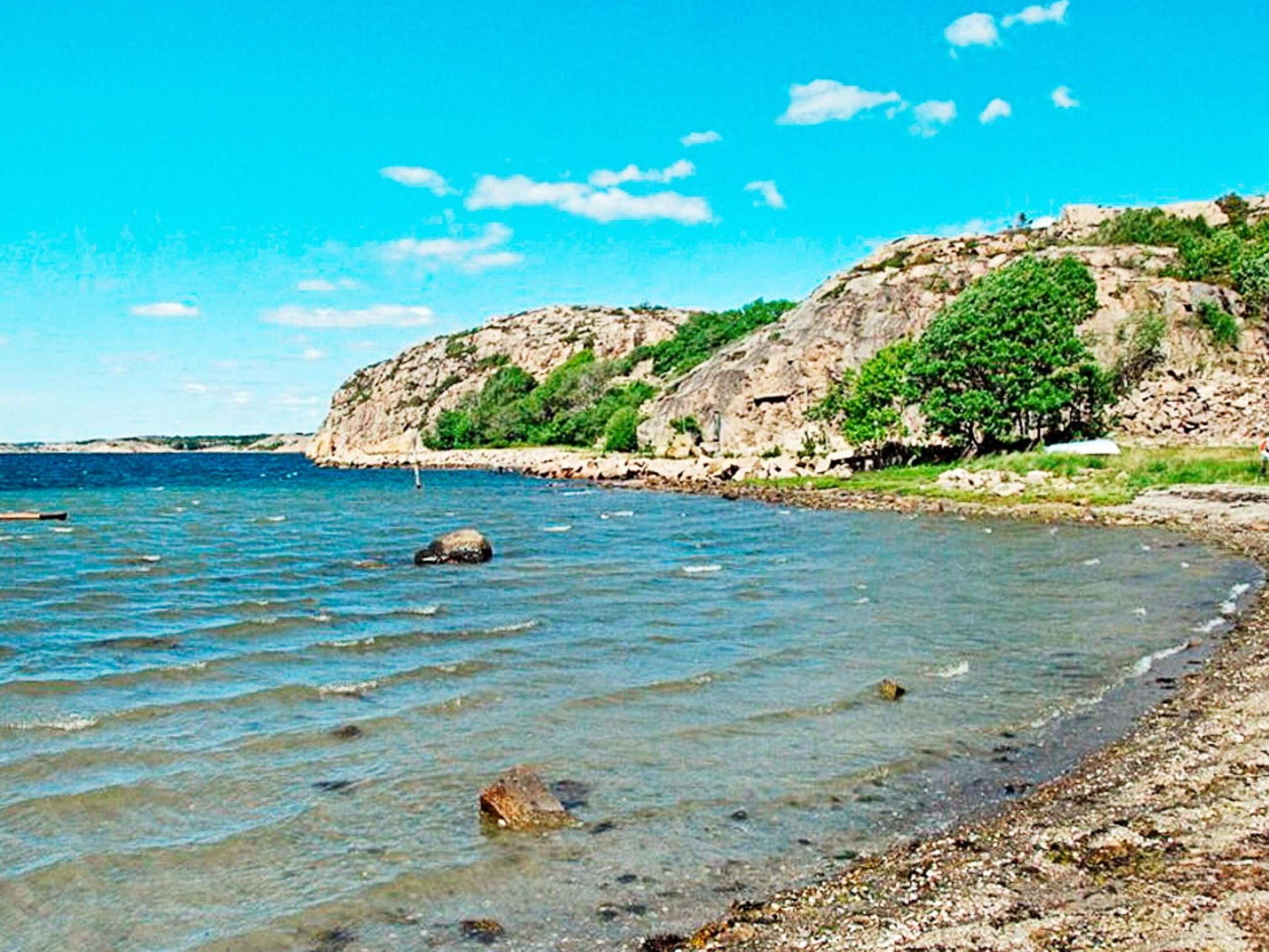 Paisaje costero con agua cristalina, costa rocosa y un acantilado con vegetación.
