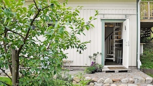 A white building with a tiled roof, a wooden deck, and a stone pathway leading to the entrance. - Holiday Home in Fjällbacka (Fjallbacka)