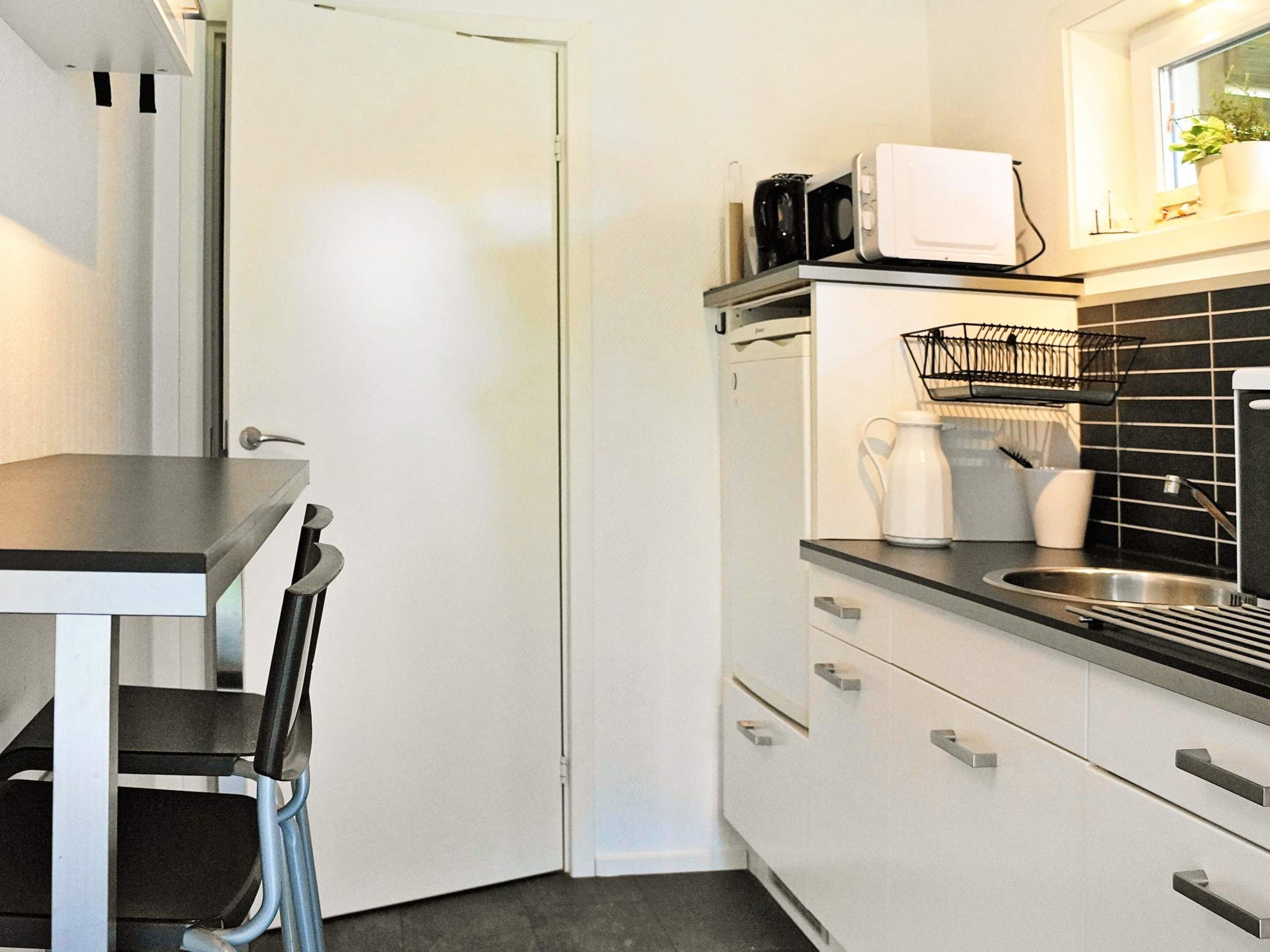 Una cocina compacta con una puerta blanca, una encimera negra y un lavamanos.