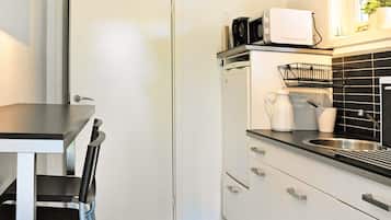 Una cocina compacta con una puerta blanca, una encimera negra y un lavamanos.