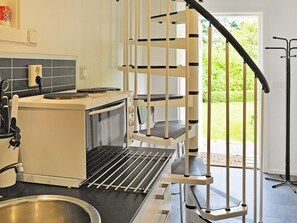 A kitchen with a built-in oven, a microwave, and a sink. There is a staircase leading to an outdoor area.