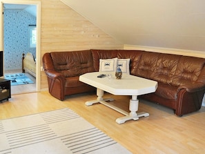 Un sofá de cuero marrón con una mesa blanca, una alfombra estampada y piso de madera.