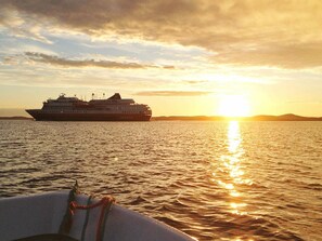 A cruise ship at sunset with calm waters and distant land.