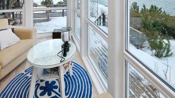 A cozy room with a large window, a round table, and a sofa.