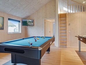 A pool table with balls, a television, and a wooden wall.