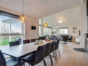Een moderne eethoek met een lange tafel, zwarte stoelen en hanglampen.