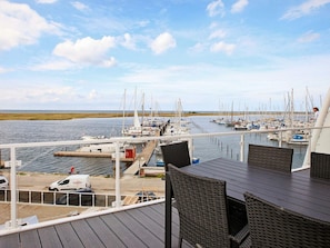 A marina with boats docked, a dockside area with chairs, and a view of the water and sky. - Holiday Home in Wendtorf (Wendtorf)