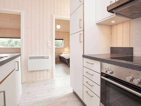 A modern kitchen with white cabinetry, a black countertop, and a built-in oven. There is a window providing natural light and a view of the outdoors.