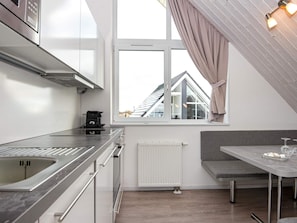 A modern kitchen with a built-in oven, a coffee maker, and a window with a view of a house.