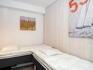 A bedroom with a bed, a wall-mounted artwork, and a wooden panel wall.