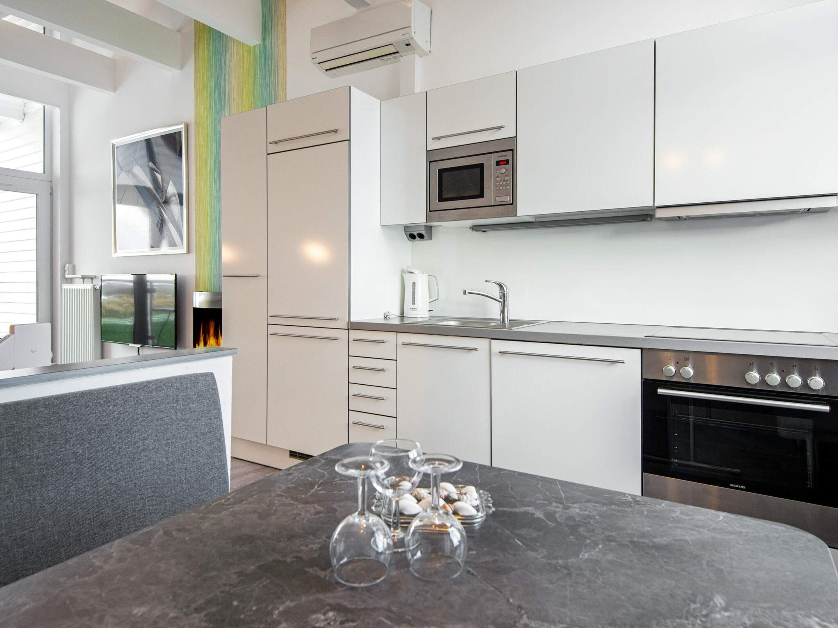 A modern kitchen with white cabinets, a stainless steel oven, and a microwave.