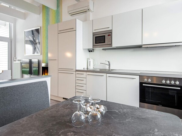 Una cocina moderna con armarios blancos, horno de acero inoxidable y microondas.