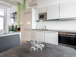 Una cocina moderna con armarios blancos, horno de acero inoxidable y microondas.