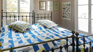A bed with a blue and white checkered bedspread and two pillows, a metal bed frame, and a window with a view of the outdoors. - 6 Person Holiday Home in Lysekil (Lysekil)