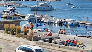 A marina with boats docked, a dockside area with people, and a rocky hillside in the background. - 6 Person Holiday Home in Lysekil (Lysekil)