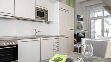 A modern kitchen with white cabinets, a built-in microwave, a stove, and a window overlooking a fire.
