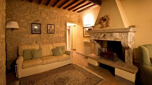 Ein gemütliches Wohnzimmer mit Steinwand, Kamin, einer Couch und einem gemusterten Teppich.