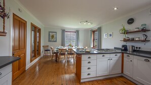 Uma cozinha com armários de madeira, uma ilha central e um espaço de jantar com cadeiras e uma mesa.