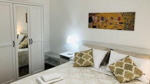 A bedroom with a bed, a nightstand, a lamp, a wardrobe, and a painting on the wall.
