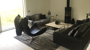A modern living room with a sofa, a black chair, a coffee table, and a fireplace. - Red Stag With Stunning Loch and Waterfall View (Crianlarich)