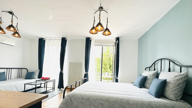 Une chambre à coucher avec un grand lit, deux tables de chevet, un bureau et une fenêtre avec des rideaux.