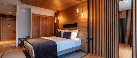 A modern bedroom with a wooden ceiling, a bed with a dark headboard, and a large mirror on the wall.