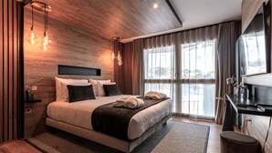 Une chambre d’hôtel moderne, dotée d’un grand lit, de lampes de chevet, d’un bureau avec un ordinateur et offrant une vue sur l’extérieur.