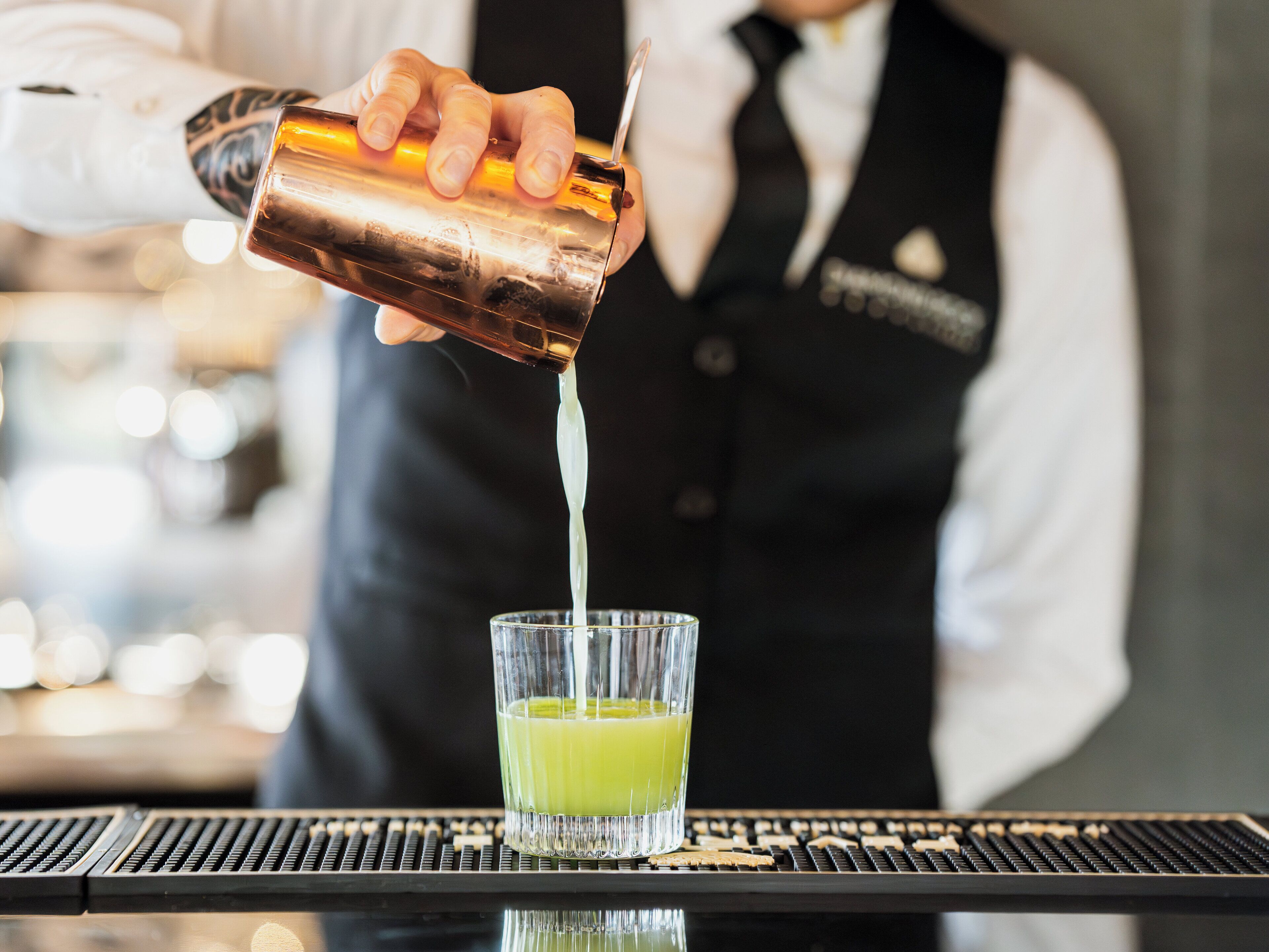 A bartender pouring a drink into a glass.