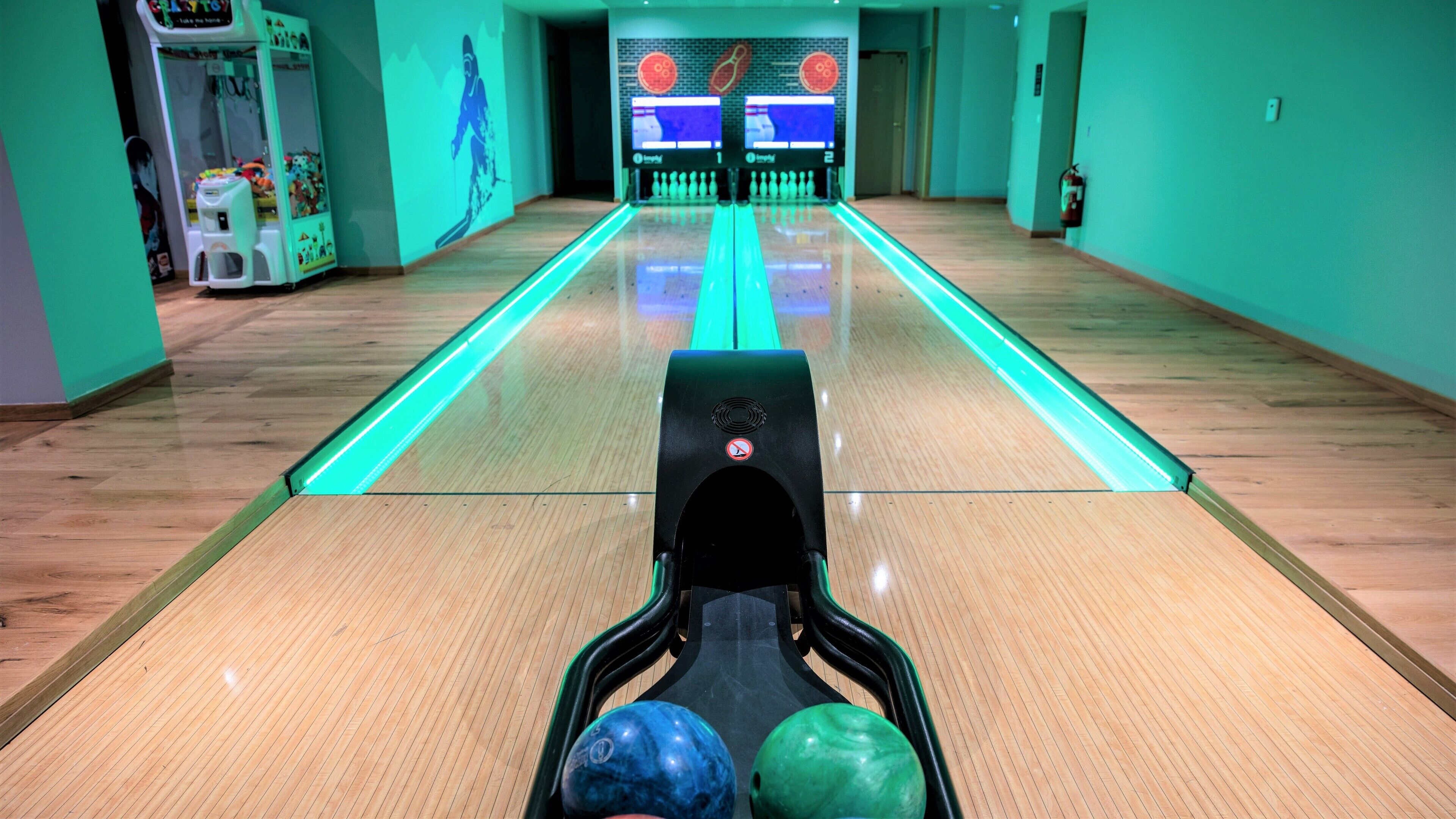 Une salle de bowling avec des pistes, un présentoir à boules de bowling et une boule de bowling.