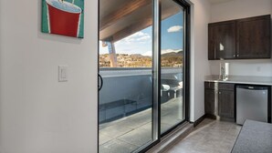 A modern kitchen with dark cabinets, a dishwasher, and a view of a snowy landscape through a sliding glass door.