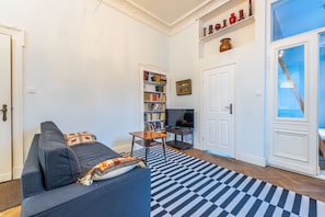 Un soggiorno con divano, libreria, televisore e tappeto decorato.