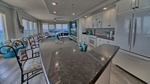 A spacious kitchen with white cabinets, a large island, and a view of the ocean.