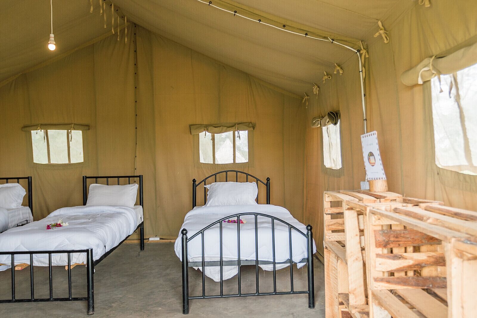 Alojamiento con carpa, dos camas, muebles de madera y una pequeña mesa.