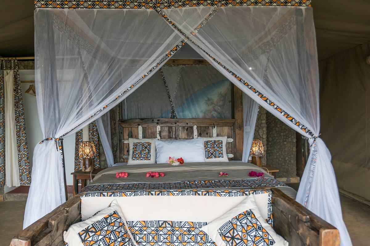 A bed with a canopy, patterned bedding, and decorative pillows.