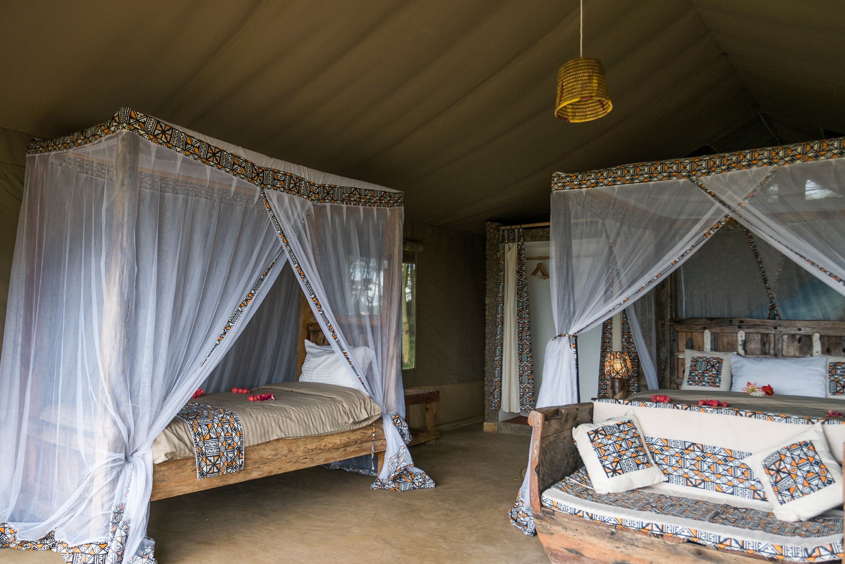 A room with two beds, each with a canopy and patterned bedding.