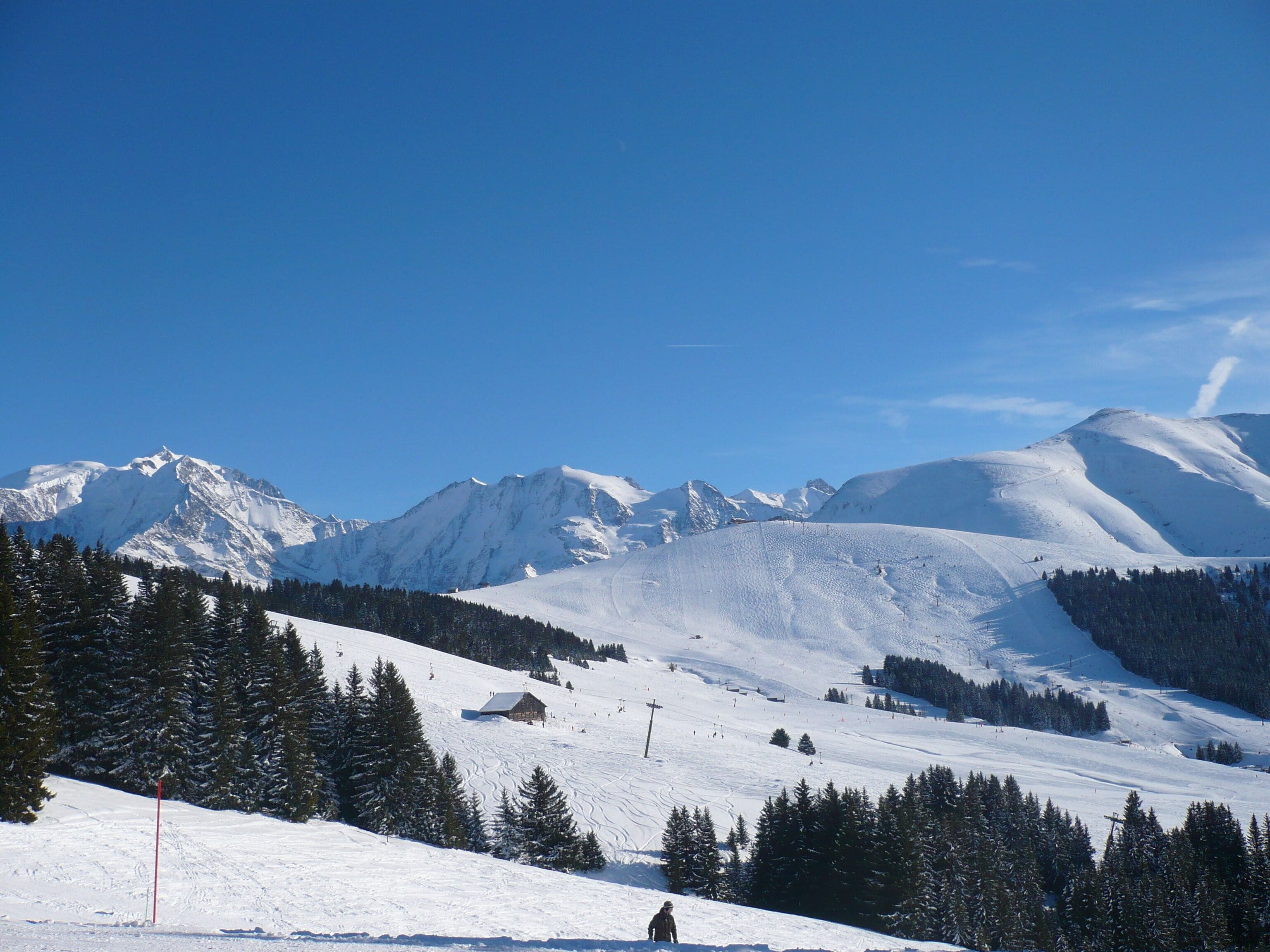 A snow-covered mountain landscape with ski slopes, a ski lift, and a small cabin.
