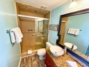 Ein Badezimmer mit Duschkabine, Toilette, Waschbecken mit Granitplatte und Spiegel.