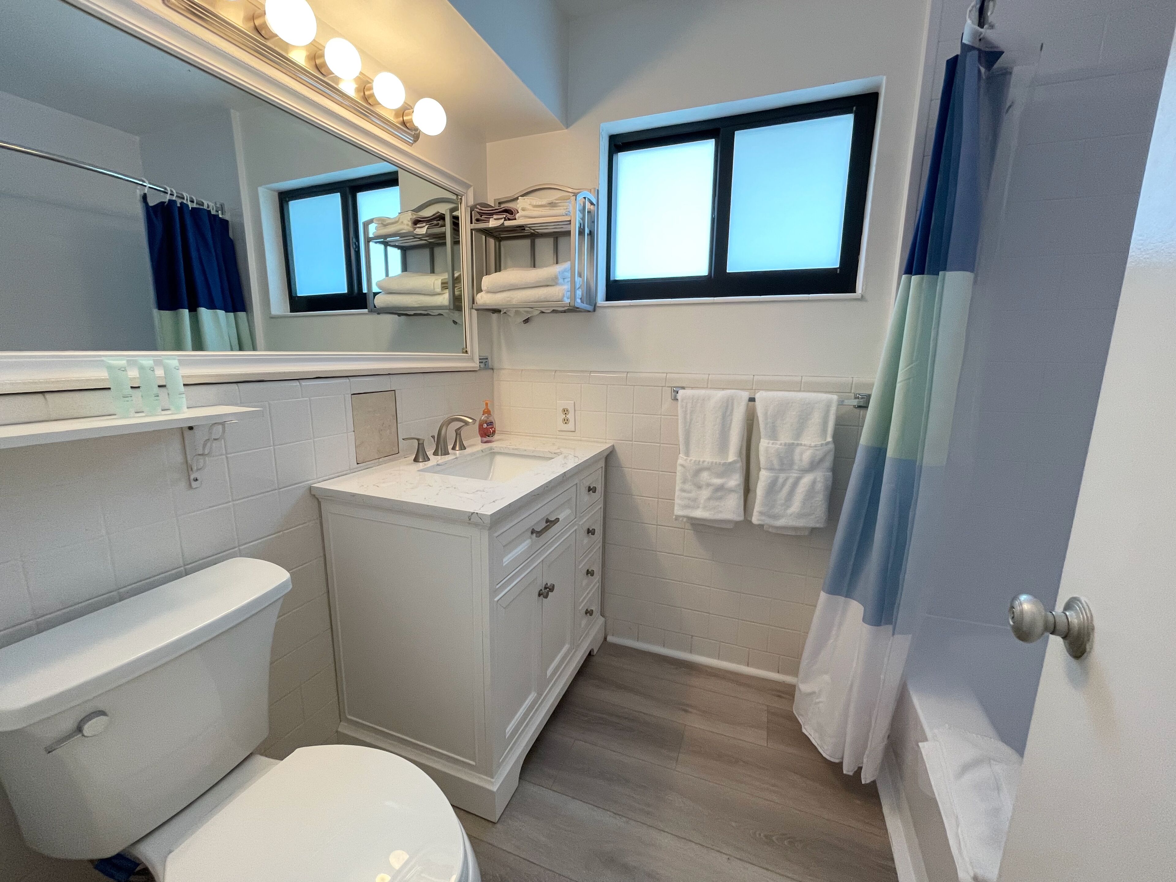 Une salle de bain équipée de toilettes, d’un lavabo, d’un miroir et d’un porte-serviettes.