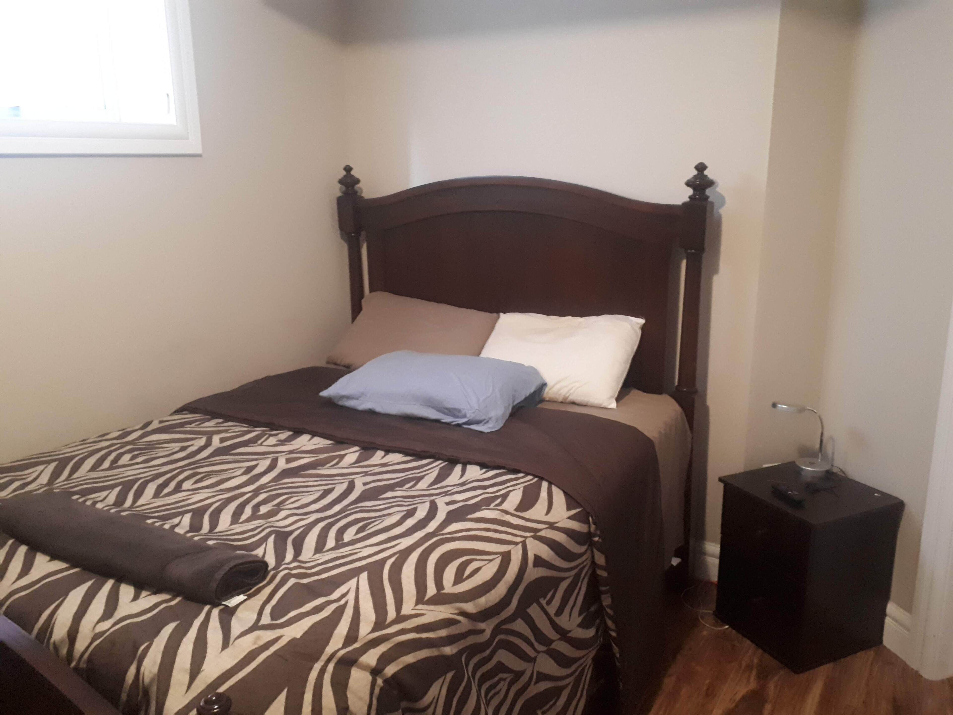 Un lit avec une couvre-lit à motifs zébrés, une tête de lit en bois et deux oreillers.