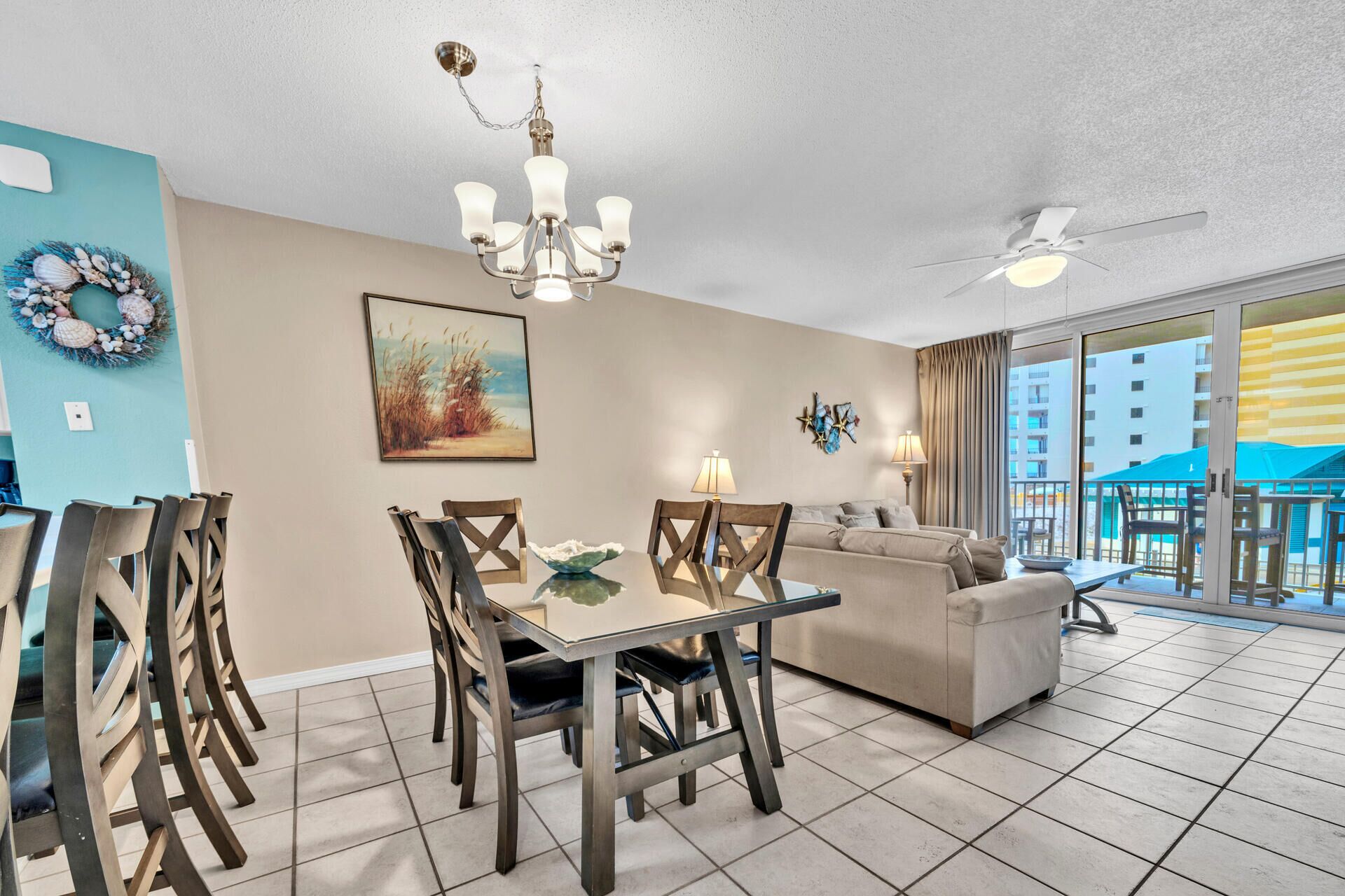 A hotel room with a dining area, a sofa, a chandelier, and a ceiling fan.