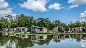 A row of modern cabins with large windows, situated by a calm lake, surrounded by lush greenery. - Water Lodge in Schaijk by the Waterside (Schaijk)