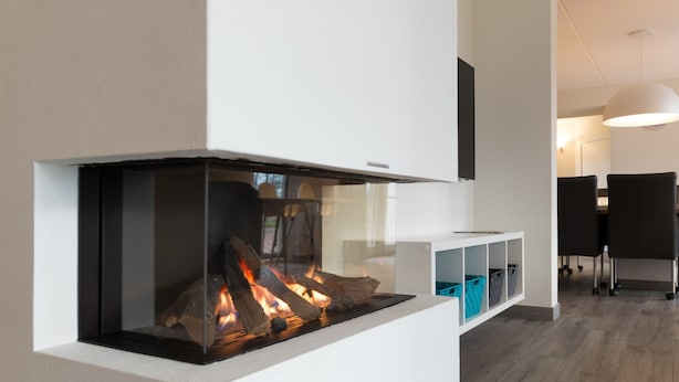 Ein modernes Interieur mit einer integrierten Feuerstelle, einem weißen Konsolentisch mit Aufbewahrungsboxen und einem Essbereich mit Stühlen und Tisch.