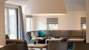 Ein modernes Wohnzimmer mit Sofa, Couchtisch und Esstisch.