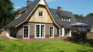 Ein zweistöckiges Haus mit steiler Satteldachform, Backsteinfassade und großen Fenstern.