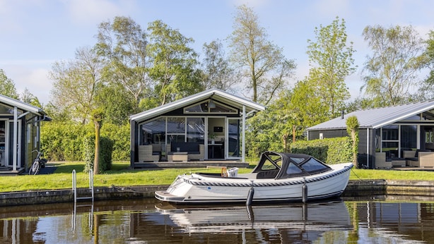 Ein Boot liegt an einem Kanal, im Hintergrund ein Haus.