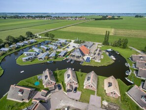 Vue aérienne d’un quartier résidentiel situé au bord de la rivière, avec des maisons, un port de plaisance et un pont.