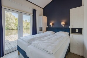 Une chambre avec un lit, une porte-fenêtre coulissante donnant sur un balcon et un mur d’accent de couleur bleu foncé.