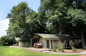 Ein Campingplatz mit zwei Zelten, Picknicktischen und einer Rasenfläche.